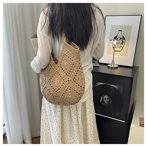 Détail du motif floral creux crocheté à la main sur un sac à bandoulière en paille chic