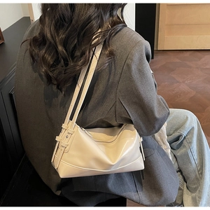 Detail of a beige faux leather underarm bag featuring adjustable straps and zipper closure