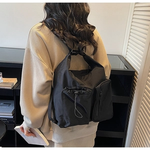 Detail of black nylon crossbody bag featuring multiple functional pockets and drawstring closure