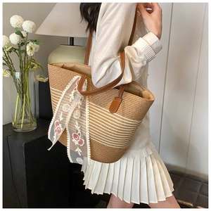 Straw tote bag with brown leather handles and floral lace scarf detail for summer