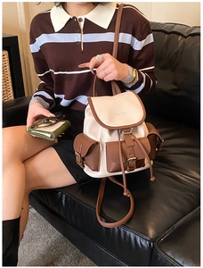 Detailed view of vintage cream and brown backpack with buckle pockets on a leather sofa