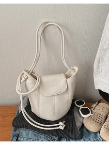 Detail of off-white lychee texture bucket bag with vertical stitching and gold hardware