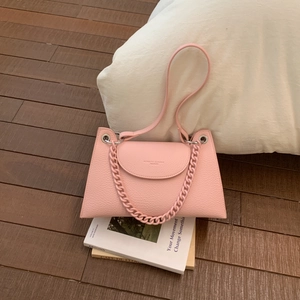 Detailed close-up of pink pebbled leather shoulder bag with chain strap and gold logo