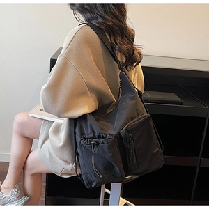 Detail of black nylon crossbody bag with drawstring pocket and utility zipper design