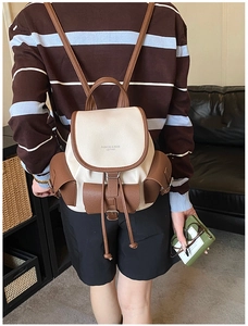 Close-up of leather backpack featuring drawstring closure and textured pockets