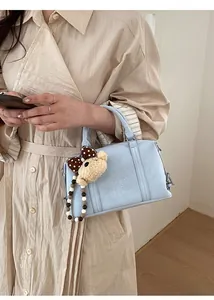 Close-up of light blue Boston bag with bear pendant and ZSKERT AIR PARIS embossed text