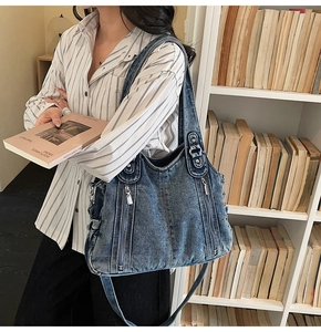 Detail of vintage denim crossbody bag featuring double zipper pockets and metal buckles