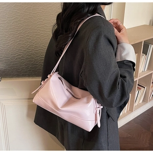 Side view of a pink soft leather underarm bag worn with a stylish grey blazer suit