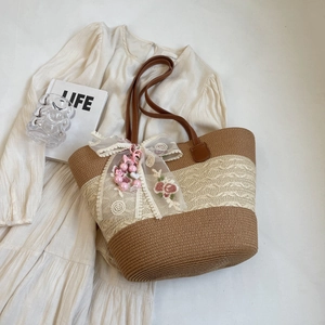 Detail der gewebten Strohtasche mit floraler Spitzen Schleife, Perlen und Ledergriffen