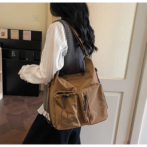 Detail view of brown canvas crossbody bag with multi-pockets and drawstring side pouch