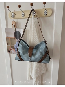 Detail of vintage-style blue shoulder bag with brown leather strap and snap closure