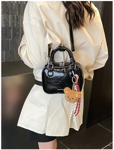 Détail du mini sac à main noir brillant avec breloque ours et texte du logo de mode