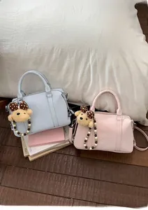 Detail of light blue and pink Boston bags featuring cute teddy bear charms and pearl accents