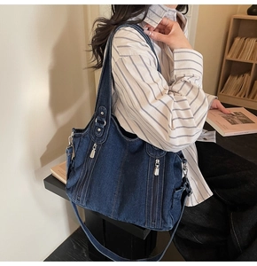 Detail of blue denim tote bag featuring side zippers and metallic silver hooks