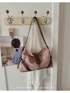 Close-up of pink suede vintage shoulder bag with brown leather straps hanging on a wall hook