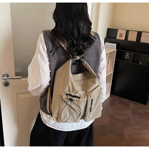 Detail of khaki utility canvas backpack with multi-pocket design and drawstring closure