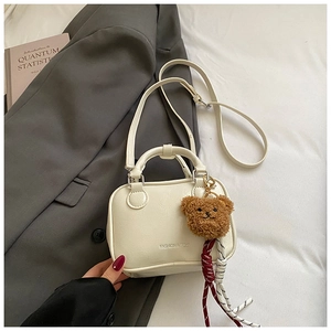 Détail du sac Boston blanc crème avec texture grainée et pendentif ours mignon