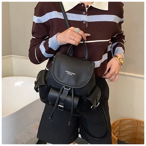 Close-up of model holding a black litchi leather backpack with multiple pockets