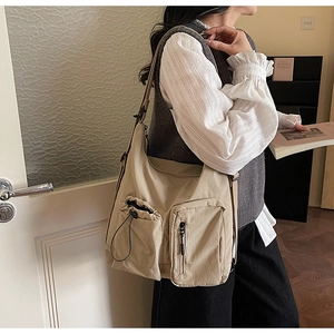 Detail of khaki canvas crossbody bag featuring functional drawstring pockets and wide strap