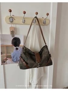 Detail of vintage canvas shoulder bag with leather trim hanging on a wooden hook
