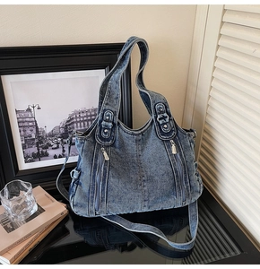 Detail of vintage blue denim shoulder bag with front double zippers and thick handle
