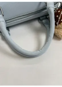 Detail of light blue Boston bag showing round padded handles and silver hardware