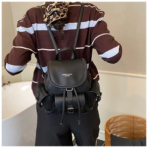 Detail view of black lychee grain leather backpack with drawstring and flap closure