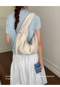 Detailed view of cream white crescent hobo bag with drawstring on model shoulder
