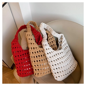Close-up of three handmade crochet tote bags in red, beige and khaki colors on a chair