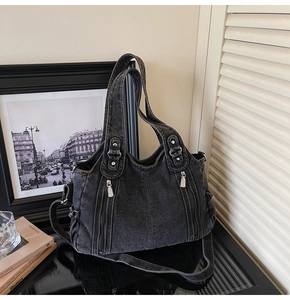 Detailed close-up of washed black denim handbag with silver zippers and dual straps