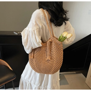 Detailed macro view of the woven hollow texture and hanging tassels on the straw shoulder bag