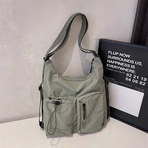 Detail of light green multi-pocket nylon crossbody bag with drawstring and zip pockets