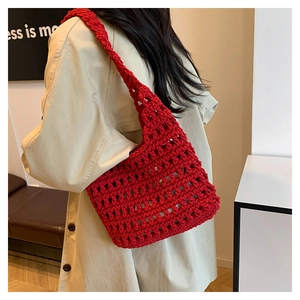 Detail of red hand-woven hollow crochet tote bag showing bold mesh texture and wide strap
