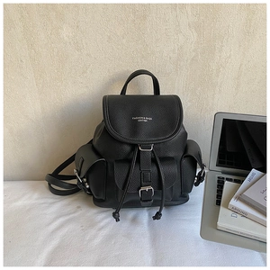 Detail of a black lychee texture leather backpack with flap cover and metal buckle