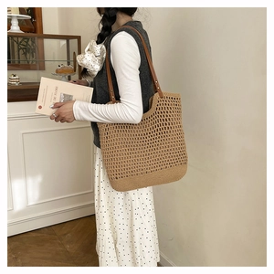 Close-up of handmade straw woven tote bag featuring durable leather straps and rivets
