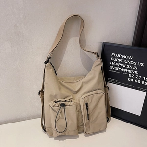 Detail of khaki nylon crossbody bag showing drawstring and zipper pockets with adjustable strap