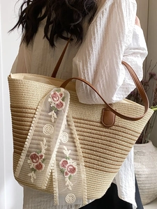 Straw tote bag with floral embroidery and brown leather strap for beach vacations