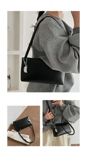 Detail view of minimalist black leather baguette bag with silver crescent moon chain detail