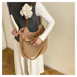 Detail view of woven straw tote bag featuring brown leather straps and interior pocket