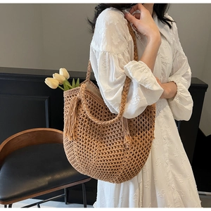 Detailed hollow weave texture on a natural straw shoulder bag with stylish fringe tassels