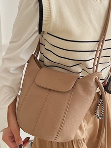 Chic beige pebbled leather bucket bag with Lucky charm, perfect for spring office commuting