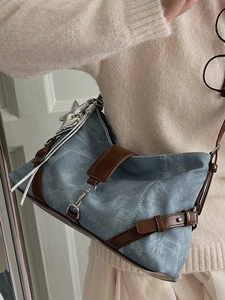 Blue denim underarm shoulder bag with brown leather accents and silver hardware details