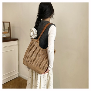 Detail of hand-woven straw tote bag with brown leather handles and hollow mesh texture