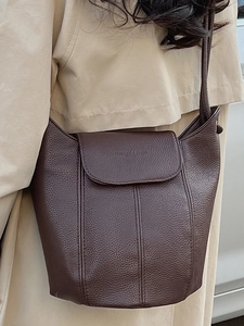 Deep brown leather bucket bag with pebble texture styled with a beige trench coat