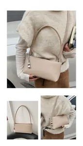 Detailed macro view of beige faux leather handbag with silver chain and metal pendant