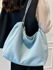 Fashion light blue denim tote bag with chain strap shown on a model shoulder