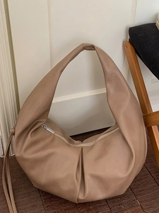 Minimalist beige pleated crescent tote bag with leather texture and silver zipper detail