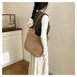 Detailed close-up of handmade woven straw tote bag with brown leather strap and rivets