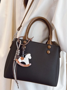 Minimalist black crossbody bag with brown handles and a white rocking horse charm