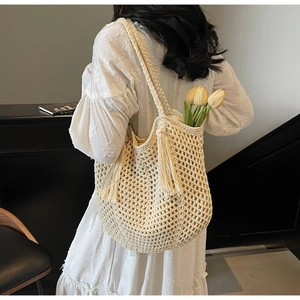 Detail of hollow woven cream tote bag with stylish long tassels and thick straps